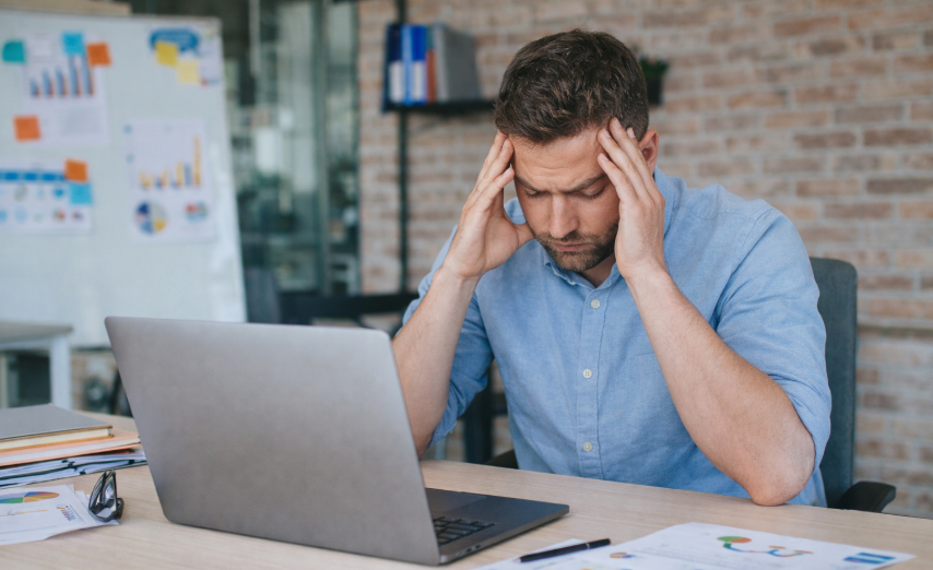 Emprendedor frustrado frente a su computadora buscando soluciones a sus problemas financieros